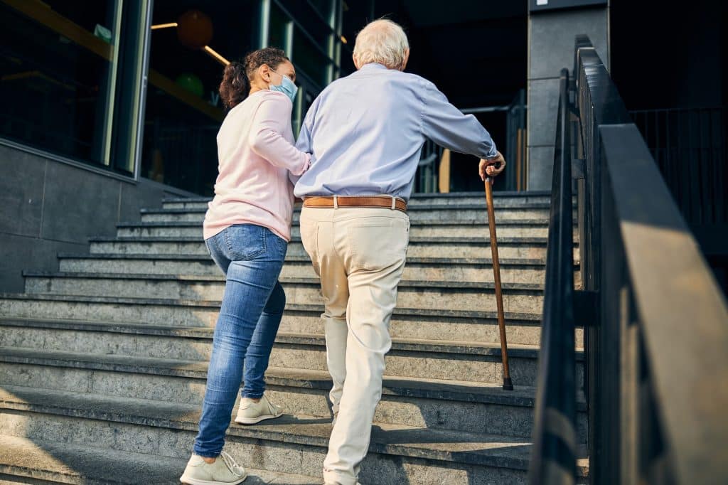 Mujer ayudando a anciano a subir escaleras