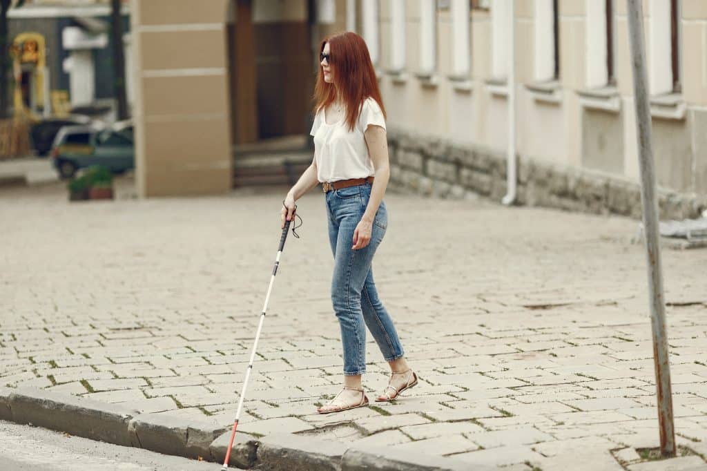 Mujer ciega bajando un bordillo alto