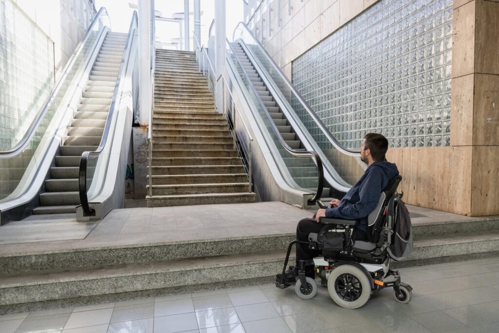 Hombre con movilidad reducida viendo una escalera sin accesibilidad